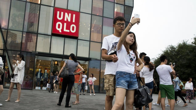 A Chinese couple take a selfie outside the Uniqlo flagship store where a steamy video purportedly taken inside one of its fitting room showing a couple apparently having sex went viral online in Beijing, Thursday, July 16, 2015. While online searches for the Japanese clothing brand soared after the viral spread of the video, it has also drawn the concern of the police and China's highest web regulator who are investigating whether it was a vulgar marketing gimmick. (AP Photo/Ng Han Guan)